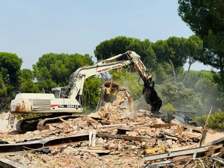 Excavadora blanca de Coty Demoliciones realizando el derribo técnico de una nave industrial en Madrid